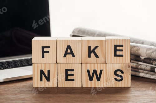 Preview: wooden cubes with words fake news, laptop and newspapers on wooden tabletop