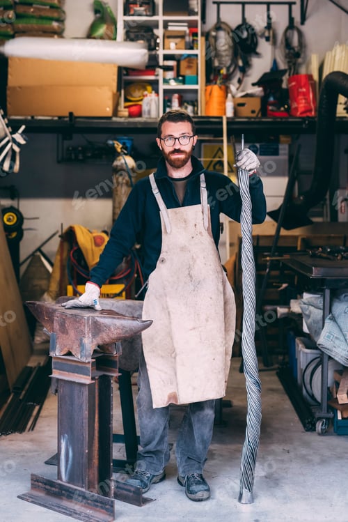 Preview: Portrait of metalworker leaning on anvil in forge workshop