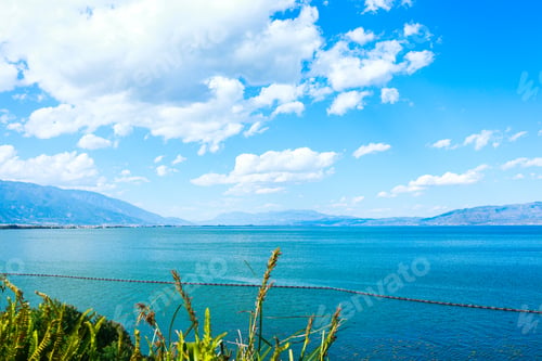 Preview: Scenic view of a blue tranquil lake surrounded by mountains on a sunny day