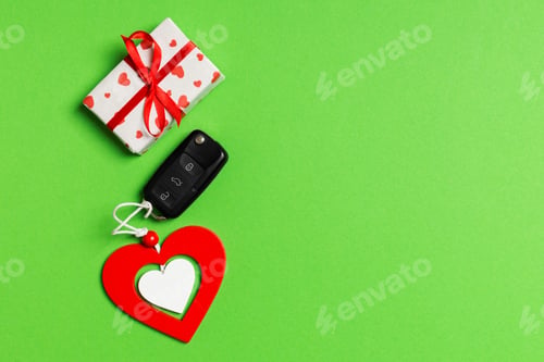 Preview: Top view of gift box, car key and wooden heart on colorful background