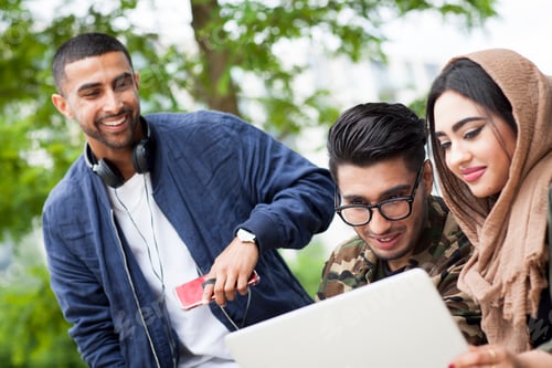 Preview: Three friends outdoors, looking at laptop