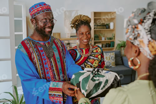 Preview: Smiling Black Man and Woman Giving Wrapped Gift during Kwanzaa Celebration