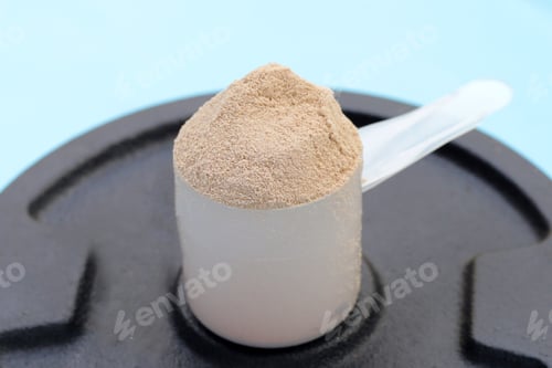Preview: Whey protein powder with iron weight plates on blue background.