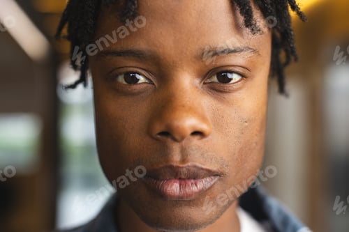 Preview: African American man with short dreadlocks looking at camera in a modern business office