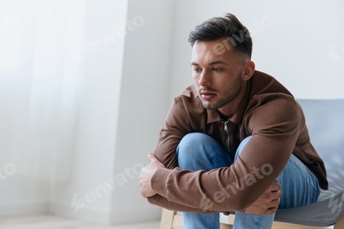 Preview: Upset sad frustrated suffering young man guy hugs him knees looks aside have big mental psychology