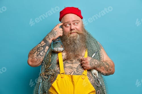 Preview: Photo of serious boatswain rubs temple and looks thoughtfully aside has tattooed body contemplates a
