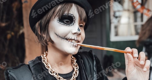 Preview: Beautiful scary little girl celebrating halloween, chewing gummy worm. Terrifying face makeup and wi