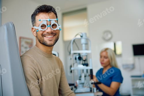 Preview: Happy man with optical testing glasses at the clinic looking at camera.