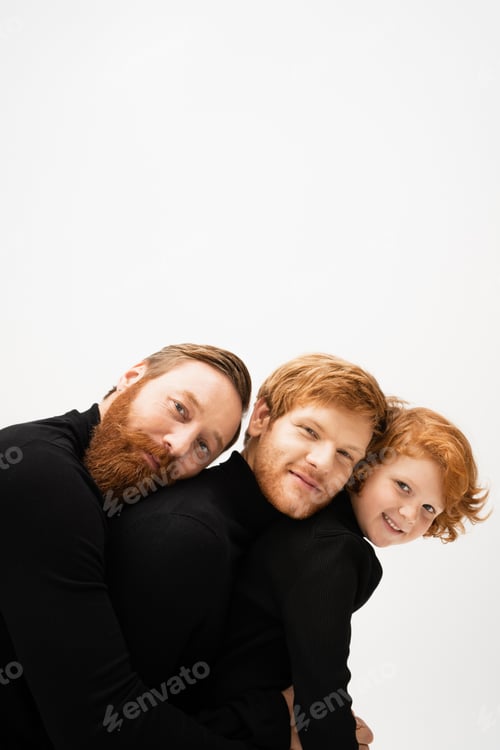 Preview: family portrait of redhead bearded men and boy in black sweaters looking at camera isolated on grey