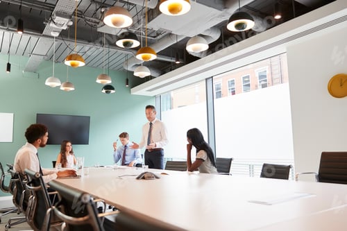 Preview: Mature Businessman Giving Boardroom Presentation To Colleagues In Meeting Room