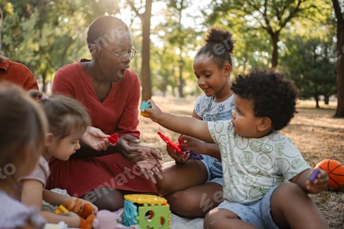Preview: Preschool teacher playing with children in the park