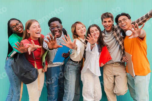 Preview: Big group of multiracial teenage students having fun and looking at camera at teal blue wall