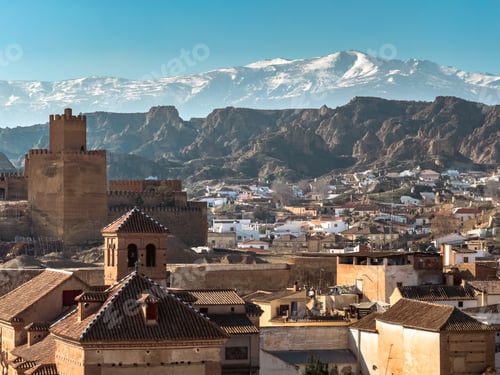 Preview: Scenic view of Guadix, Spain with castle, cave houses, and mountains
