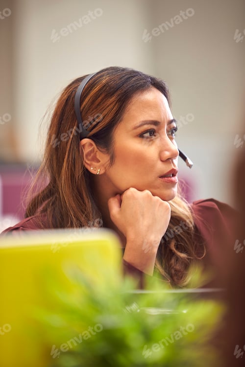 Preview: Mature Businesswoman Wearing Phone Headset Talking To Caller In Busy Customer Services Centre