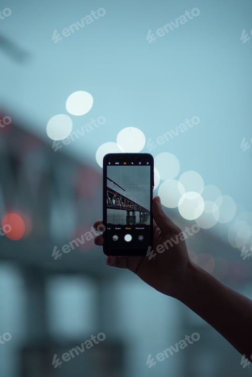 Preview: Closeup of a person taking a picture of a bridge, a vertical shot