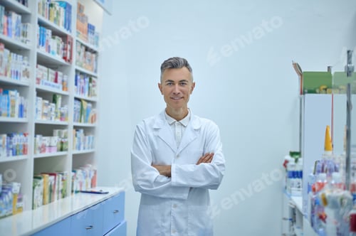 Preview: Man in a lab coat standing near the shelves with medicines