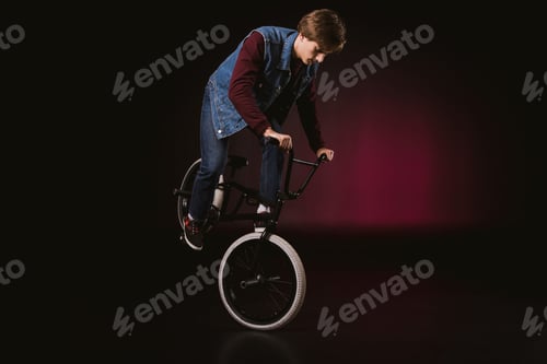 Preview: young bmx cyclist performing stunt with bike in studio