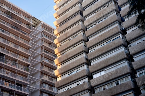 Preview: High-rise apartment buildings with balconies under a clear blue sky at sunset.