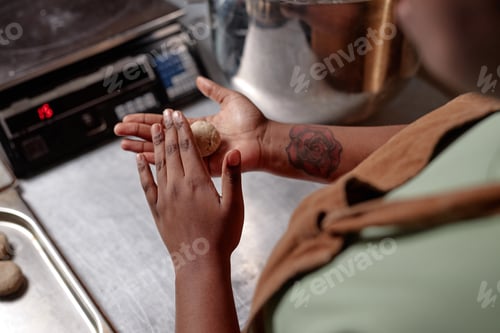 Preview: Black Female Baker Rolling Dough into Ball Making Wheat Buns in Commercial Kitchen
