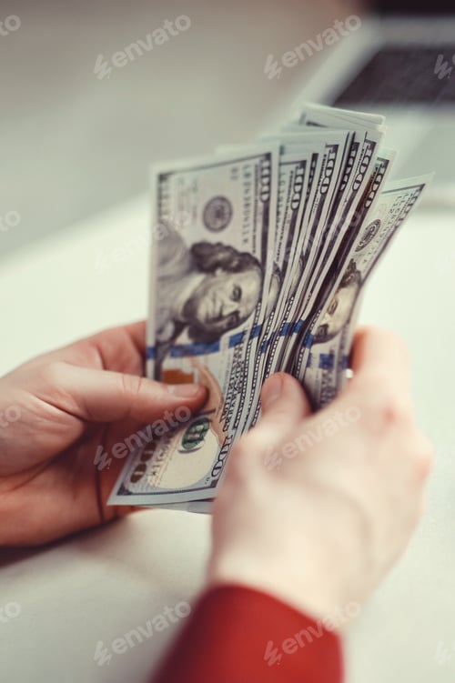 Preview: Millennial candid authentic man close up hand counting 100 usd dollars banknotes at natural light