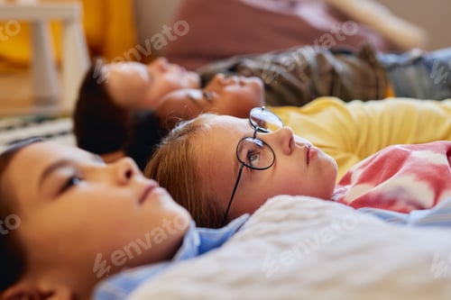 Preview: Kids Laying on Classroom Floor with Focus on Girl Wearing Glasses