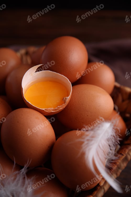Preview: Basket of fresh farm chicken eggs with broken one on a wooden rustic background