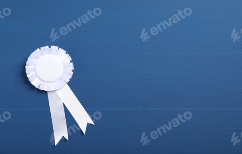 Preview: White award ribbon on blue wooden table, top view. Space for text