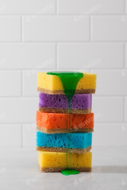 Preview: Multicolored sponges for washing dishes are stacked, green dishwashing gel flows down from above