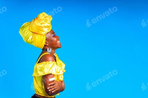 Preview: african woman in yellow silk dress blouse and turban over head showing her vaccinated arm in blue