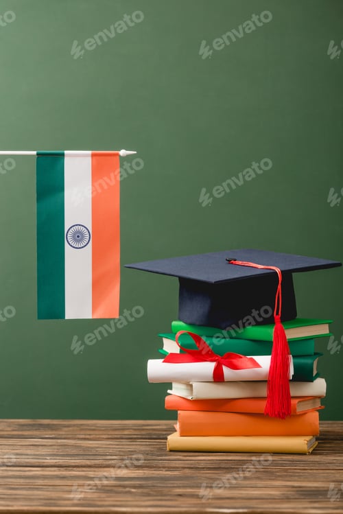 Preview: books, diploma, academic cap and indian flag on wooden surface isolated on green