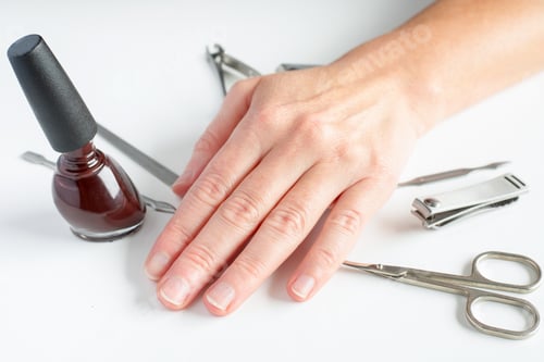 Preview: Manicure tools and female hand on white background. Making self-manicure at home concept.