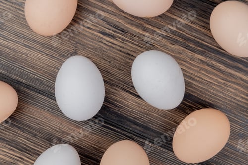 Preview: top view of white and cream colored chicken eggs isolated on a wooden background