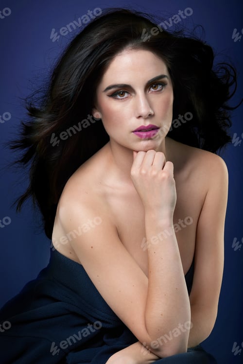 Preview: Confident in her beauty. Portrait of a beautiful young woman posing against a blue background.