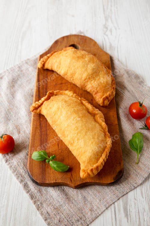 Preview: Homemade Deep Fried Italian Panzerotti Calzone on a rustic wooden board on a white wooden background