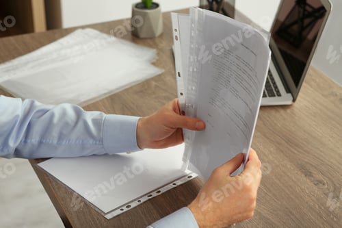 Preview: Businessman working with documents at wooden table in office, closeup