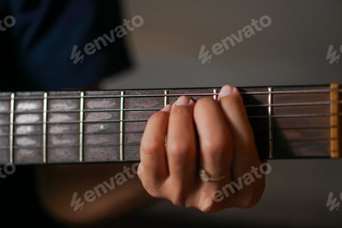 Hand Playing Guitar on Fretboard in Close-up