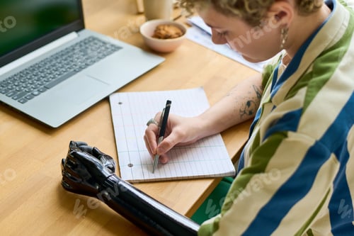 Preview: Young businesswoman with partial arm making notes or writing down plan