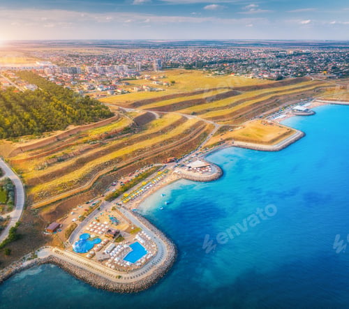 Preview: Aerial view of sandy beach, blue sea, restaurants at sunset