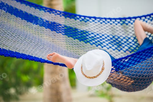 Preview: Closeup straw beach hat near relaxing young woman