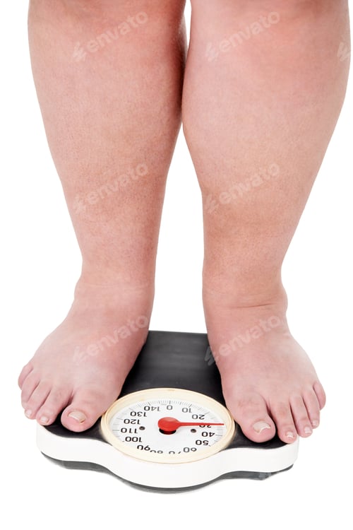 Preview: Another pound. A closeup shot of an overweight man weighing himself on a scale.