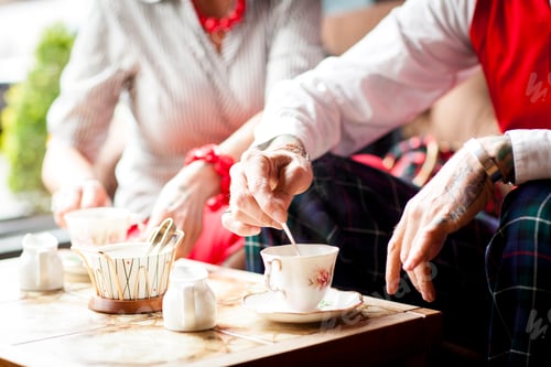 Preview: Close up of hands of senior man stirring tea in vintage tea rooms
