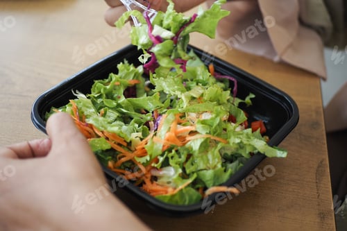 Preview: women eating salad in a plastic bowl outdoor