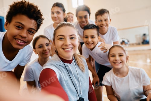 Preview: Happy PE teacher and school kids taking selfie during exercise class.