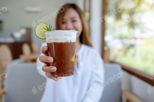 Visualização: Imagem de retrato de uma linda jovem asiática segurando e servindo um copo de café gelado
