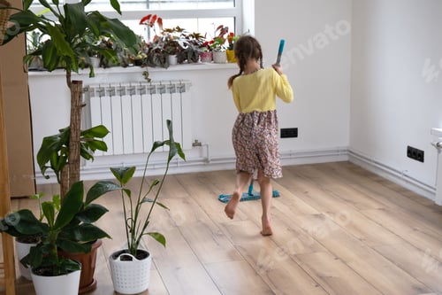 Preview: A girl dances with a mop to clean the floor in a new house - general cleaning in an empty room