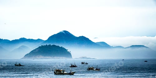 Preview: Scenic view of a fleet of boats sailing in the sea with a majestic mountain range in the background