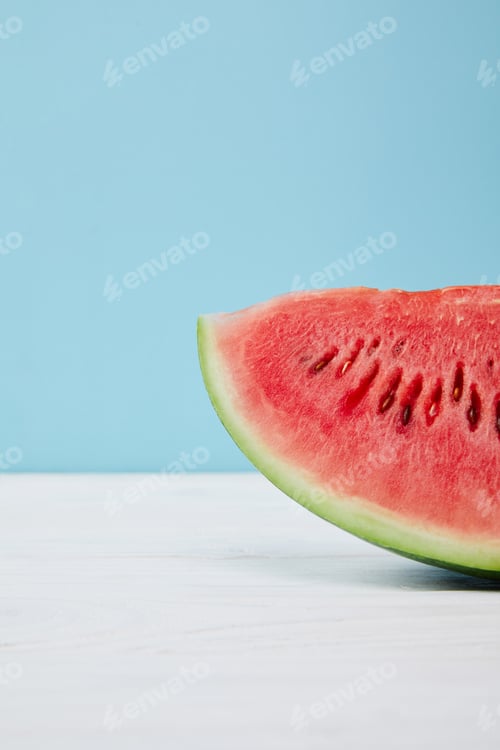Preview: close up view of fresh watermelon slice on white surface on blue background