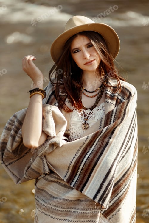 Preview: beautiful woman traveler wearing hat and poncho standing in water of river