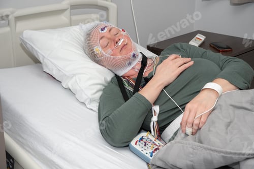 Preview: Middle aged woman measuring brain waves, examining polysomnography in sleep lab