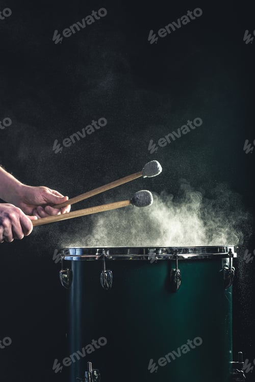 Preview: A man plays a musical percussion instrument with sticks on a dark background.